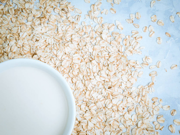 Oat milk drink in white cup and cereal flakes on kitchen bench. Flat lay. Copy space. - Zdjęcie, obraz