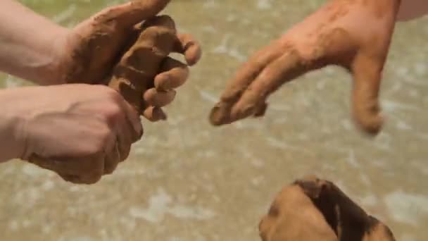 Gros plan des mains faisant de l'argile sur une plage de mer, du sable et des vagues comme arrière-plan, concept d'été et de voyage
. - Séquence, vidéo