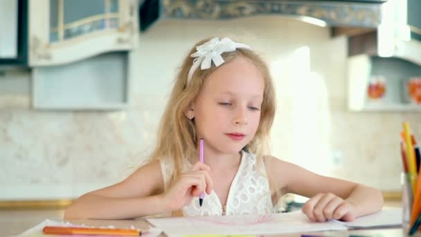 Χαριτωμένο κοριτσάκι κάθεται στο τραπέζι και ζωγραφίζει με μολύβια. - Πλάνα, βίντεο