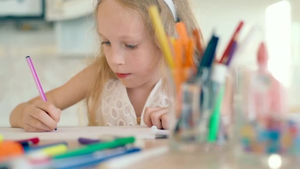 Carina bambina siede a tavola e disegna con le matite
. - Filmati, video