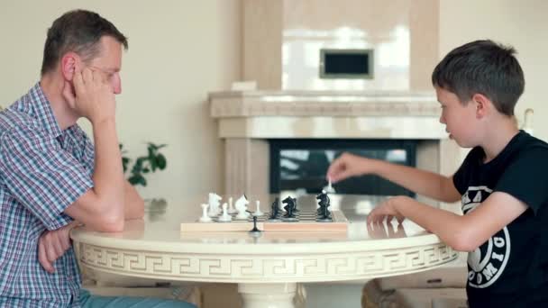 Niño feliz jugando ajedrez con un hombre mayor en casa
. - Imágenes, Vídeo