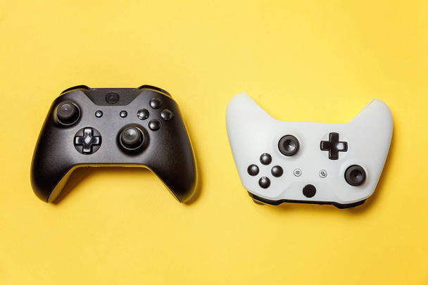 Blanco y negro dos joystick sobre fondo amarillo. Juego de ordenador competencia videojuego control confrontación concepto
 - Foto, imagen