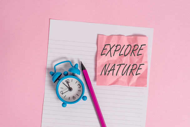 Writing note showing Explore Nature. Business photo showcasing Discovering the countryside Enjoying the wildlife Travel Striped paper sheet note pencil vintage alarm clock colored background. - Photo, Image