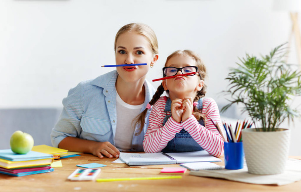 funny mother and child daughter doing homework writing and readi - Photo, Image