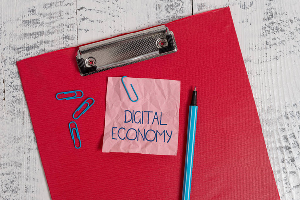 Writing note showing Digital Economy. Business photo showcasing worldwide network of economic activities and technologies Colored clipboard crushed sticky note clip marker old wooden background. - Photo, Image