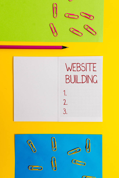 Text sign showing Website Building. Conceptual photo tools that typically allow the construction of pages Blank squared notebook pencil marker paper sheets plain colored background. - Photo, Image