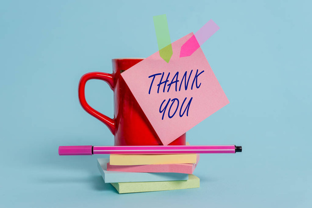 Word writing text Thank You. Business concept for a polite expression used when acknowledging a gift or service Cup sticky note arrow banners stacked pads pen lying pastel background. - Valokuva, kuva