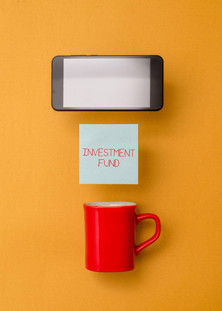 Word writing text Investment Fund. Business concept for A supply of capital belonging to numerous investors Coffee cup colored sticky note electronic device yolk color background. - Photo, Image