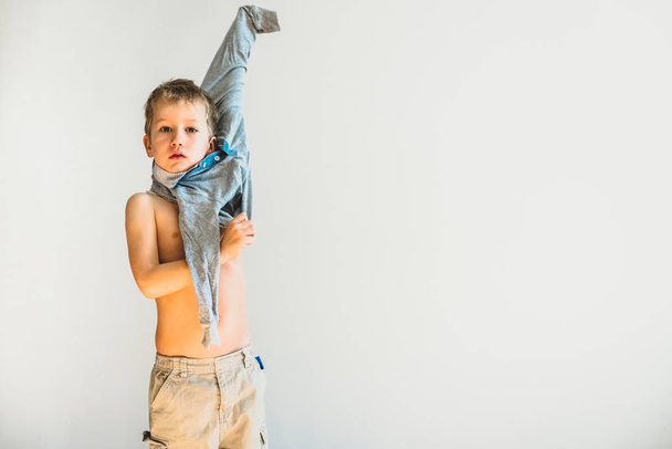 Kind proberen om opstijgen zijn hemd en uitkleden op zijn eigen. - Foto, afbeelding