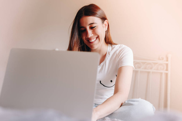 beautiful young woman smiling and writing on her laptop - Foto, Bild