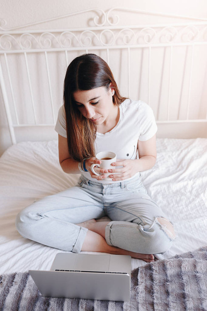 joyful female watches a film on generic laptop computer and drinking coffee - Фото, изображение