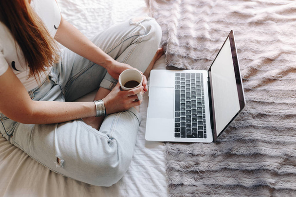 unrecognized woman drinking coffee and watching a Tv series on her laptop - Foto, afbeelding