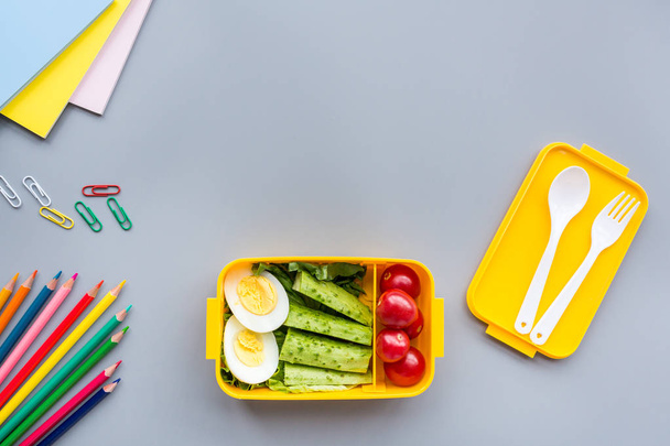 School supplies and lunch box with sandwich and vegetables. Back to school. Healthy eating habits concept - background layout with free text space. Flat lay composition, mockup, top view - Фото, изображение
