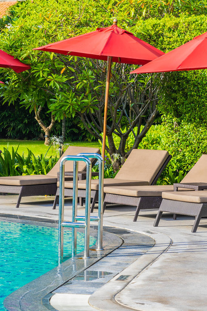 Beautiful umbrella and chair around outdoor swimming pool in hot - Foto, Bild