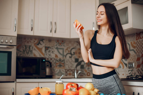 Sports girl in a kitchen with fruits - Φωτογραφία, εικόνα