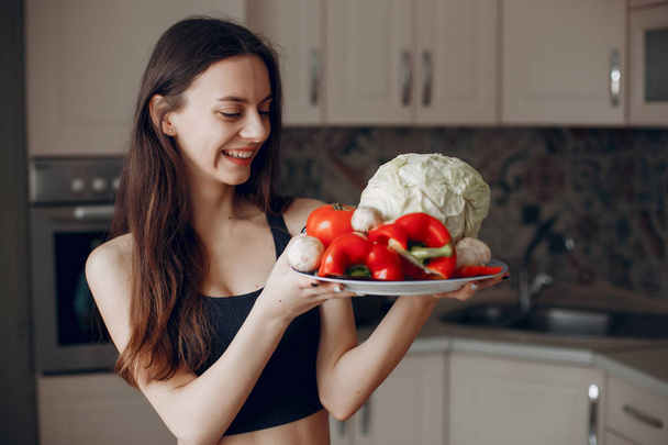 Sports girl in a kitchen with vegetables - Photo, Image