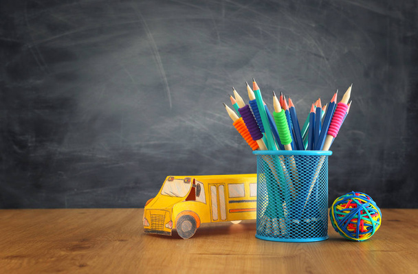 onderwijs en terug naar school concept. kartonnen bus en potloden over boeken voor Classroom Blackboard - Foto, afbeelding