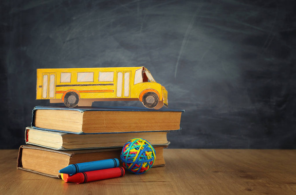 education and back to school concept. cardboard bus and books in front of classroom blackboard - Photo, Image