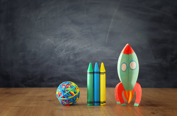 education and back to school concept. cardboard rocket and pencils in front of classroom blackboard - 写真・画像