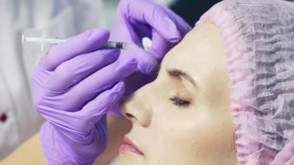 Beautiful woman getting lifting injection in the middle of the forehead. Facial cosmetology skin therapy - Séquence, vidéo