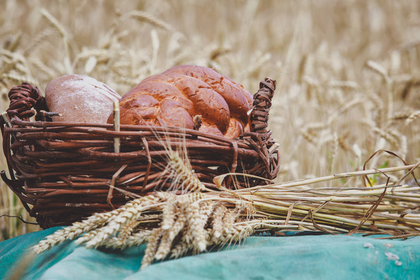 bakery products in a basket on a wheat field - Foto, Imagem