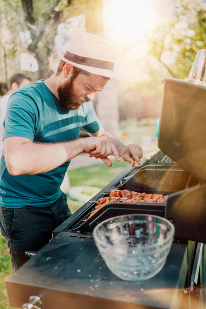 Man smiling and cooking at barbecue grill party. Friends, people lifestyle concept  - Fotografie, Obrázek
