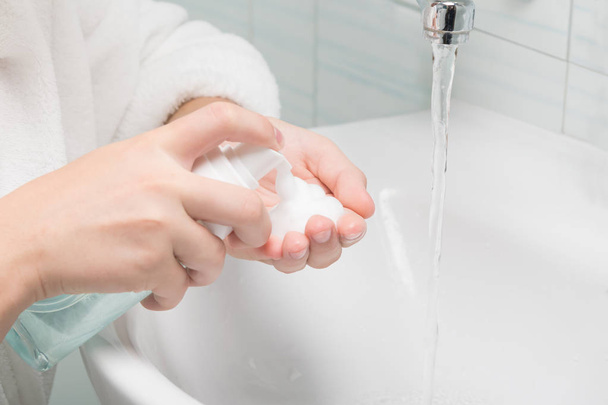 hands apply face wash foam in the bathroom, close-up - Фото, изображение