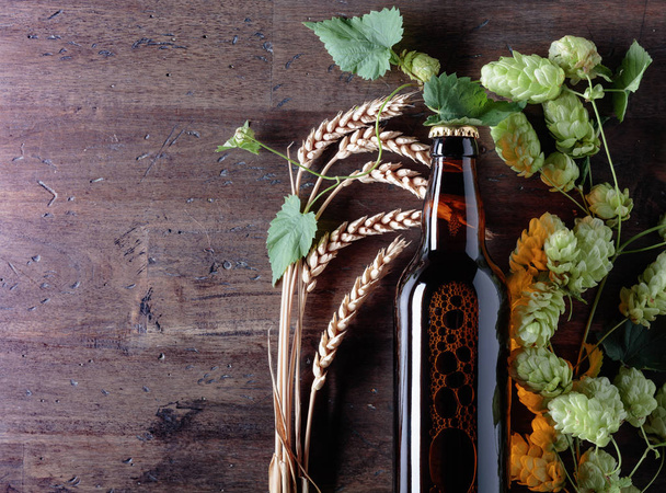 Bottle of beer, grain and hops on a old wooden background.  - Foto, imagen
