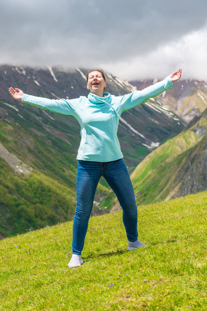 Femme émotionnelle à bras ouverts dans les montagnes jouit de la liberté
 - Photo, image