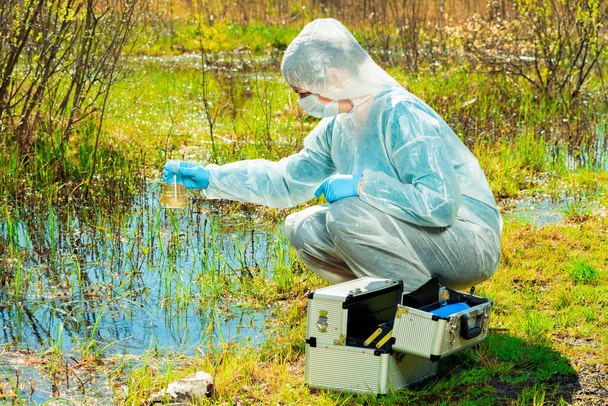 эколог на берегу лесного озера берет водяной сампл
 - Фото, изображение