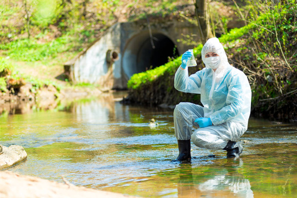 Eine Ökologin entnimmt Wasser aus einem Abwasserkanal - Foto, Bild