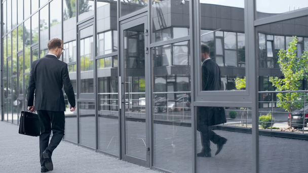 επιχειρηματίας σε τυπική φθορά με την πόρτα ανοίγματος χαρτοφύλακα και μπαίνοντας στο κτίριο - Πλάνα, βίντεο