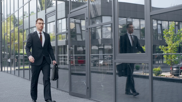 όμορφος επιχειρηματίας με χαρτοφύλακα άνοιγμα πόρτα του κτιρίου και το περπάτημα μακριά - Πλάνα, βίντεο