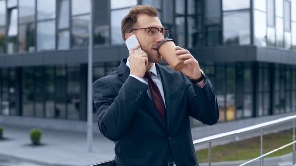 zakenman praten op smartphone, glimlachen, lachen en koffie drinken om te gaan in de buurt van gebouw  - Video