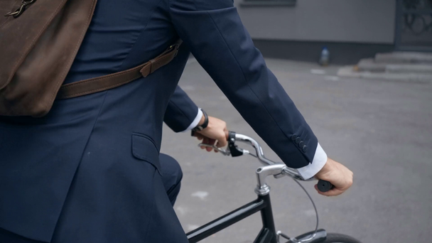 back view of businessman with backpack riding bicycle near building - Filmmaterial, Video
