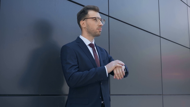 businessman in formal wear looking at watch, adjusting tie and walking away - Кадры, видео