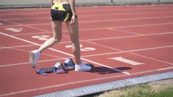 Jovem atleta feminina em posição inicial no início do bloco de cinzas Track. Estádio corrida de treinamento
  - Filmagem, Vídeo