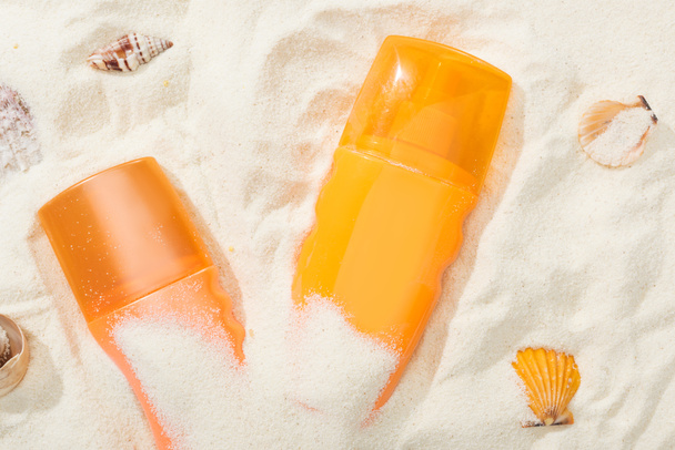 orange bottles of sunscreen lotion on sand with seashells - Photo, Image