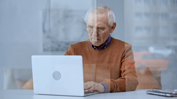 foyer sélectif du vieil homme sérieux dans la saisie de lunettes sur ordinateur portable à la maison
  - Séquence, vidéo