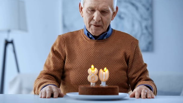 selektywne skupienie zdenerwowany emerytem patrząc na pyszne tort urodzinowy ze świecami  - Materiał filmowy, wideo