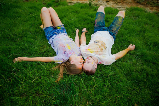 The sleeping romantic couple with multicolored powder on their bodys on the grass in park. Top view.  - Foto, immagini