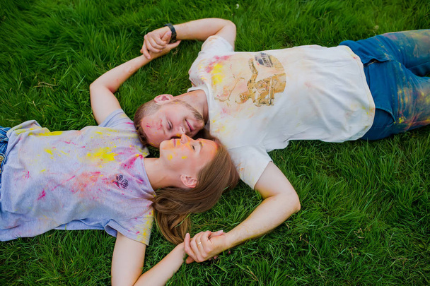 Two young people enjoying on the grass on holi festival. Top view. - Photo, Image