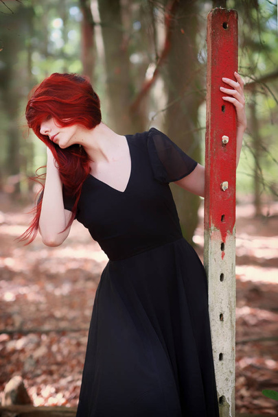 νεαρή γυναίκα με κόκκινα μαλλιά σε κομψό βραδινό φόρεμα στο δάσος - Φωτογραφία, εικόνα