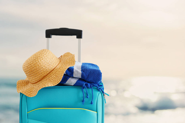 holidays. travel concept. blue suitcase with female hat and beac - Fotografie, Obrázek
