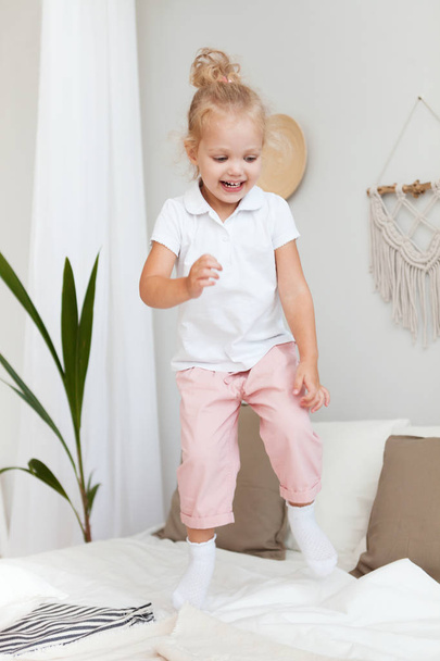 Porträt kleines hübsches lächelndes Mädchen beim Spielen und Springen im Bedro - Foto, Bild