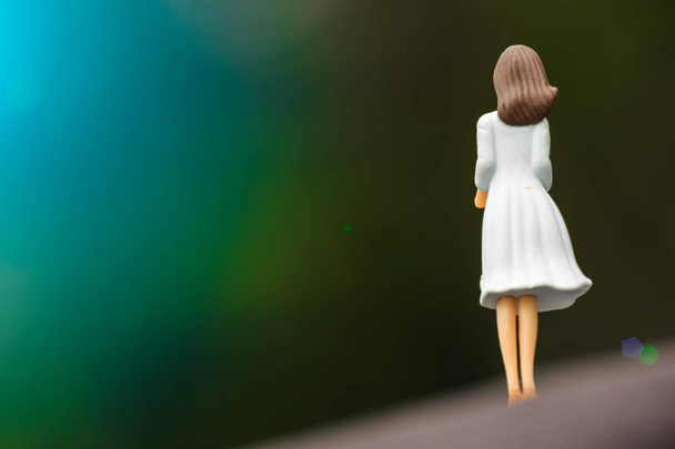 white dress girl toy figure back view in green nature - Foto, Imagen