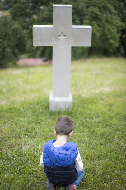 Kleine jongen bidden voor een kruis - Foto, afbeelding