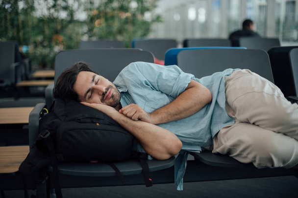 Ο τύπος στο αεροδρόμιο περιμένει την αναχώρηση, κοιμάται - Φωτογραφία, εικόνα
