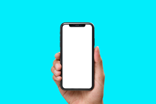 Hand holding the black smartphone with blank screen and modern frame less design on aqua colour background - Photo, Image