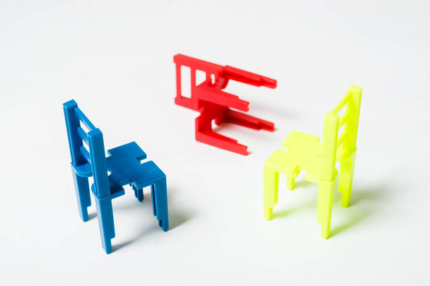 The concept of negotiation, discussion. Several multi-colored toy chairs on white background. - 写真・画像